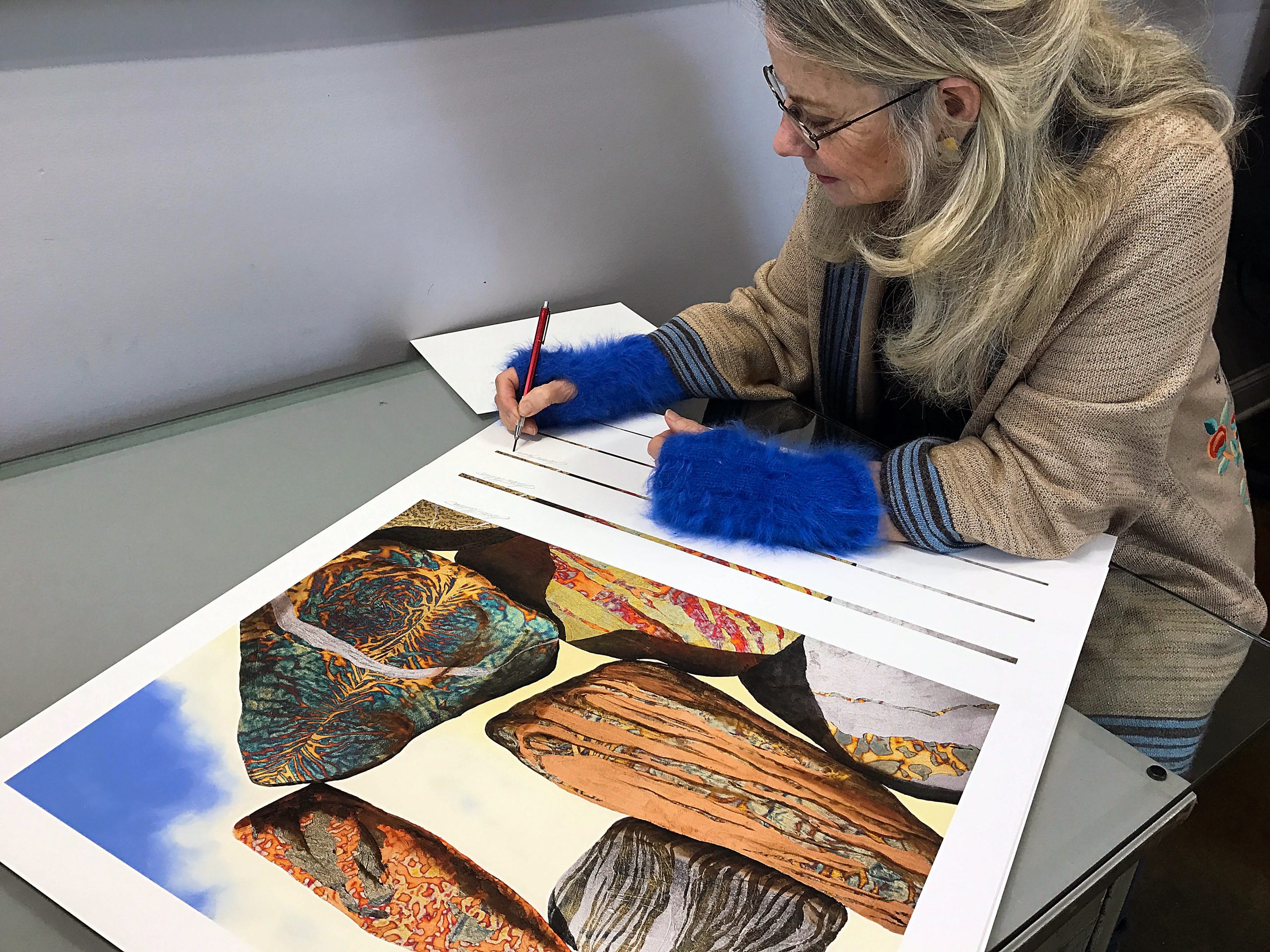 Artist Susan Makara signing a stack of fine art prints in our Virginia studio